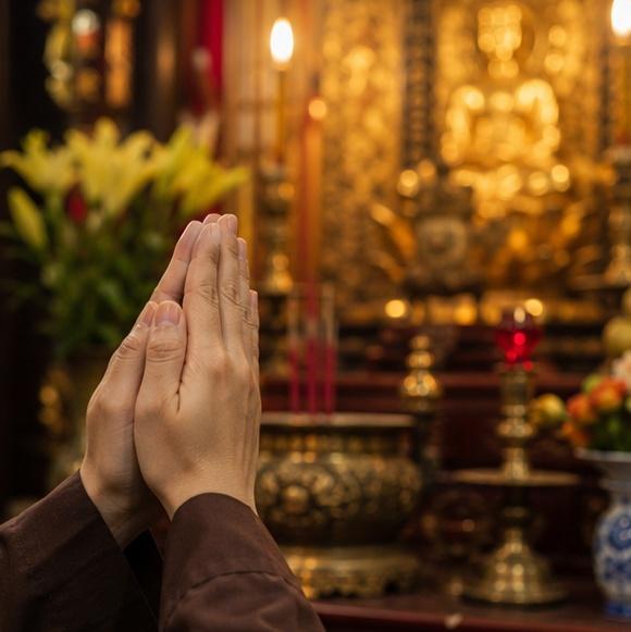 Hình ảnh đôi bàn tay chắp thành kính trước bàn thờ, ánh sáng ấm áp bao trùm không gian thiêng liêng